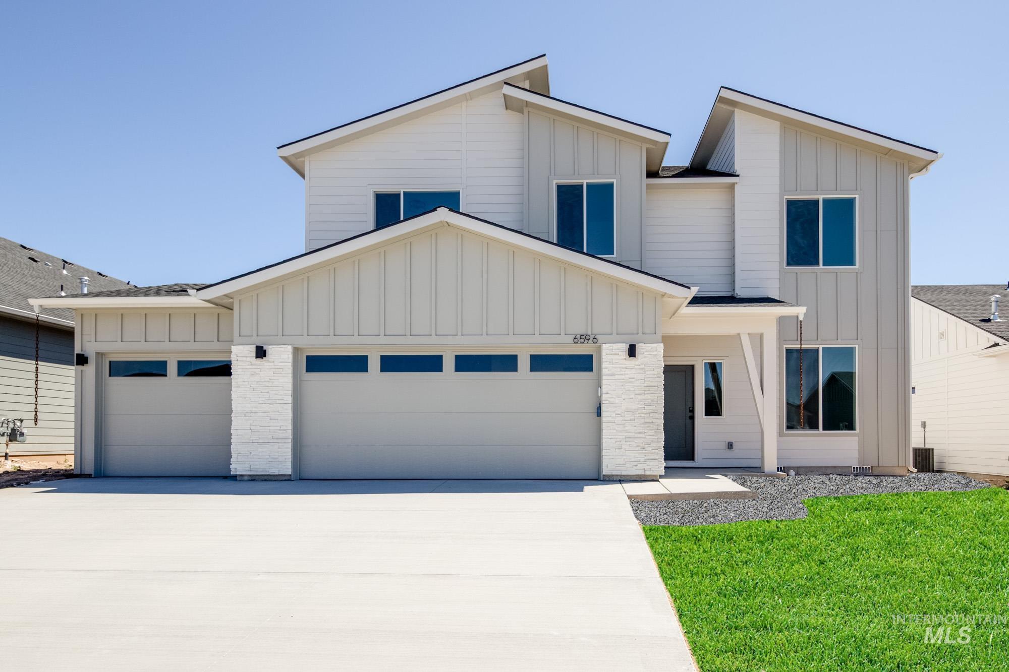 View of front of house with board and batten siding, a garage, driveway, and a front yard