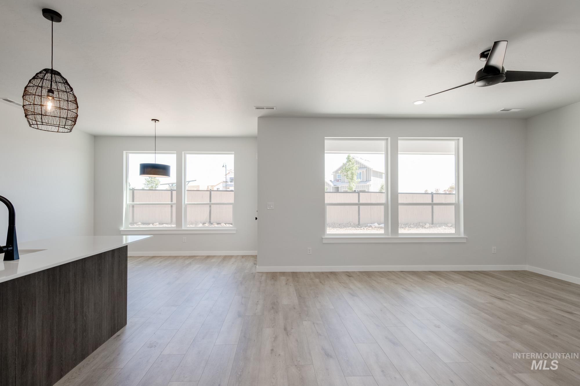 6596 South Banded Eagle Way Boise, ID 83709 - Photo 11 of 28 Unfurnished living room featuring plenty of natural light, light wood-type flooring, and a ceiling fan