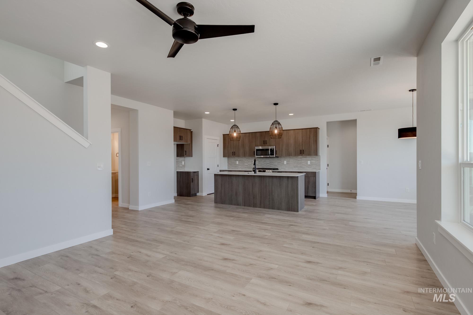 6596 South Banded Eagle Way Boise, ID 83709 - Photo 28 of 28 Kitchen featuring stainless steel microwave, open floor plan, decorative backsplash, light countertops, and recessed lighting