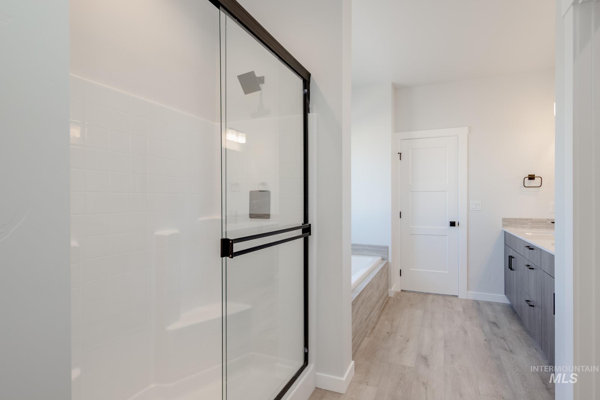 6596 South Banded Eagle Way Boise, ID 83709 - Photo 22 of 28 Bathroom with vanity, wood finished floors, a garden tub, and a shower stall