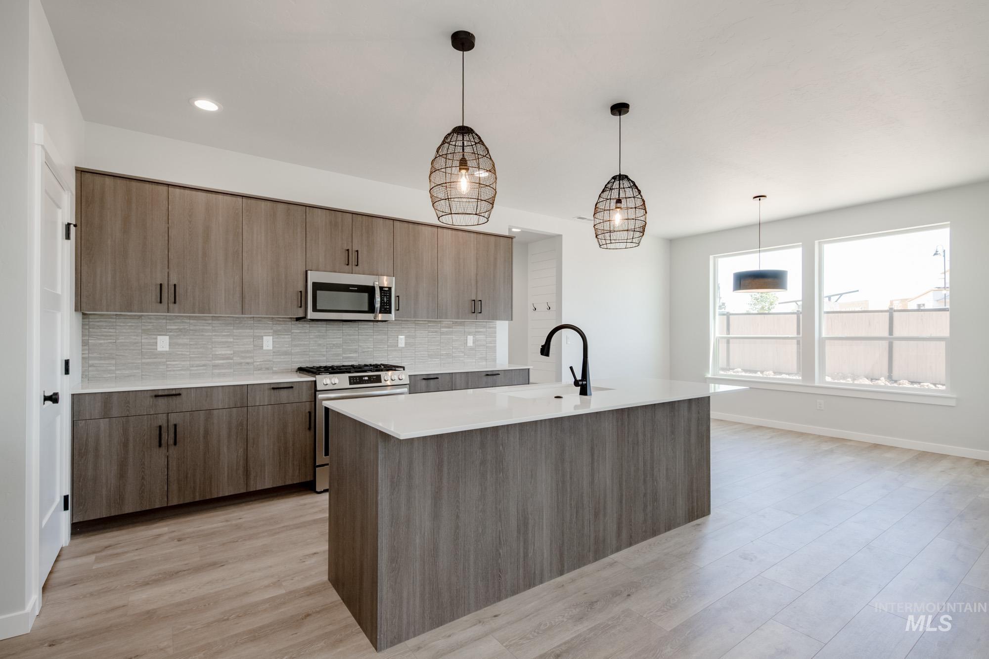 6596 South Banded Eagle Way Boise, ID 83709 - Photo 5 of 28 Kitchen with appliances with stainless steel finishes, decorative backsplash, light countertops, light wood-style flooring, and an island with sink