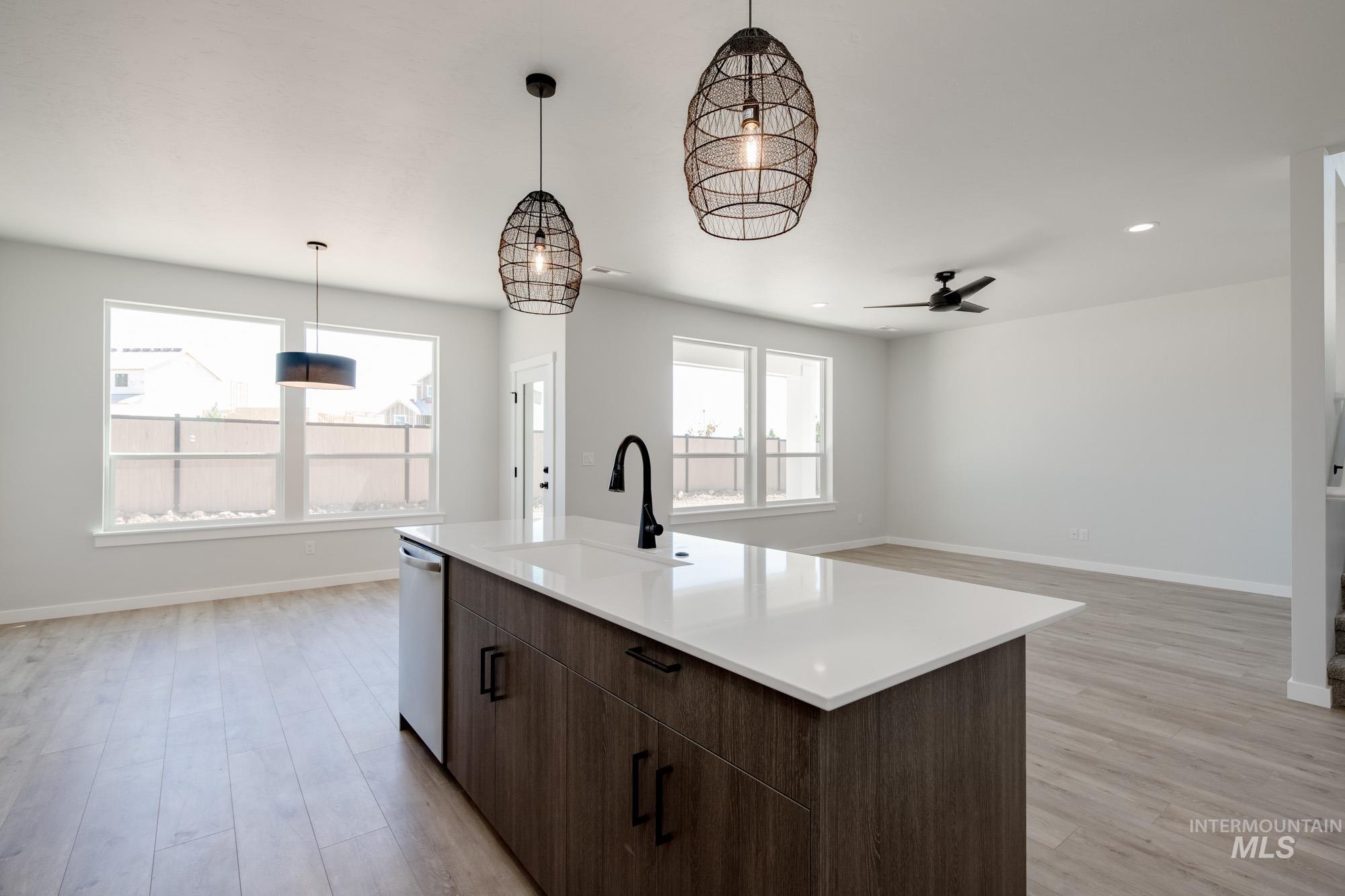 6596 South Banded Eagle Way Boise, ID 83709 - Photo 7 of 28 Kitchen with dishwasher, light wood-style floors, a ceiling fan, light countertops, and hanging light fixtures
