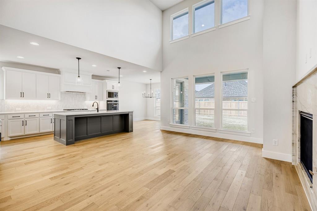 3328 Chinaberry Street Celina, TX 75009 - Photo 28 of 29 a large white kitchen with kitchen island a sink wooden floor and a refrigerator