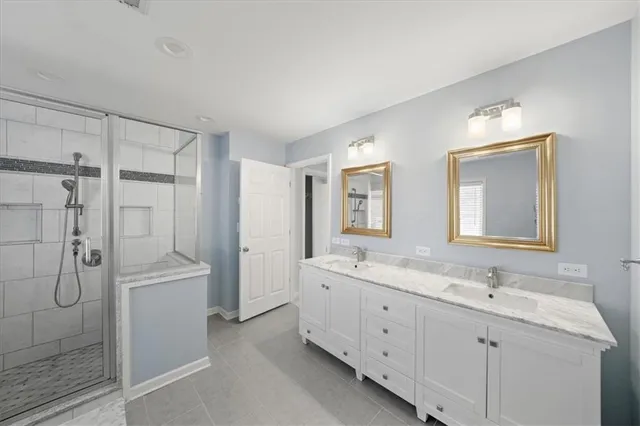 a spacious bathroom with a double vanity sink a large mirror and shower