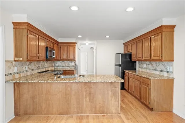 a kitchen with stainless steel appliances granite countertop a sink refrigerator and cabinets