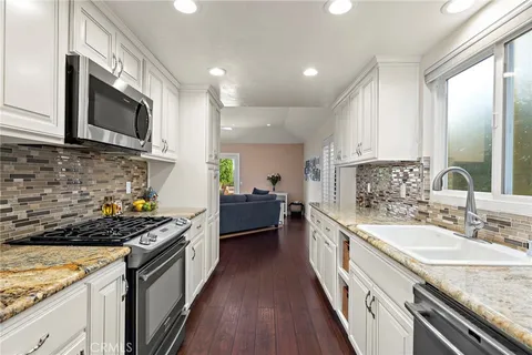 a kitchen with stainless steel appliances granite countertop a stove a sink and a microwave