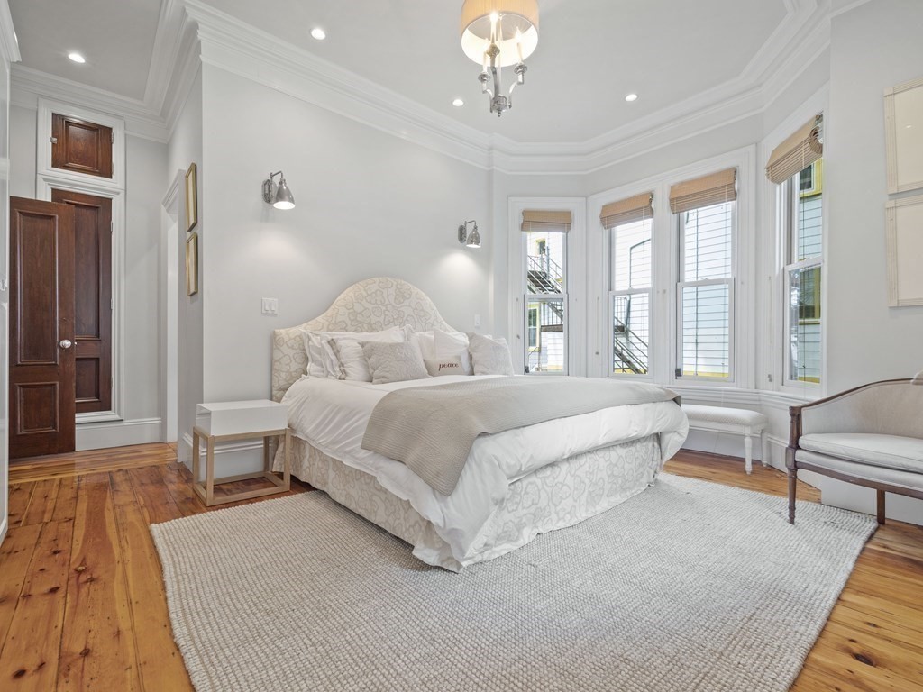 99 Sedgwick Street, Unit 1 Boston, MA 02130 - Photo 19 of 41 a spacious bedroom with a large bed and a chandelier