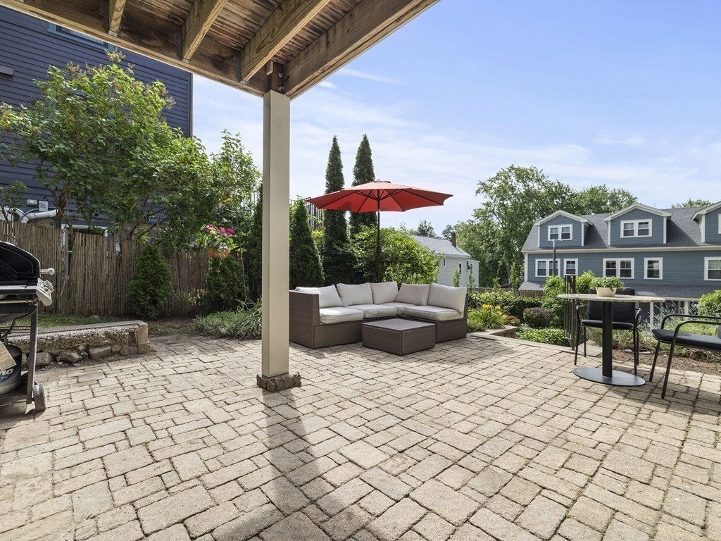 99 Sedgwick Street, Unit 1 Boston, MA 02130 - Photo 27 of 41 a view of a patio with table and chairs barbeque potted plants and large tree