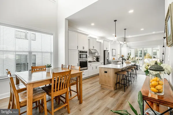 a dining room with stainless steel appliances kitchen island granite countertop a table chairs and a view of living room