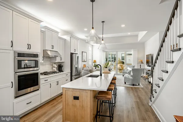 a kitchen with stainless steel appliances kitchen island granite countertop a refrigerator a stove a sink dishwasher and white cabinets with wooden floor