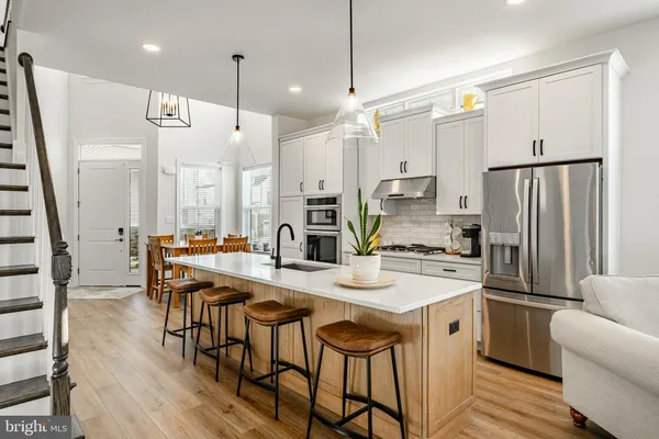 a kitchen with stainless steel appliances a refrigerator a stove a kitchen island with a dining table and chairs