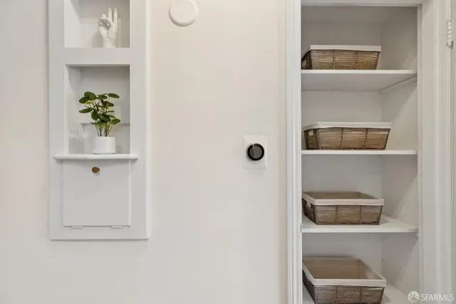 a view of a hallway with wooden floor and a bathroom
