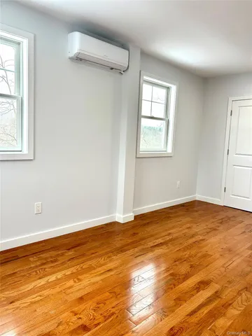 a view of an empty room with window and wooden floor