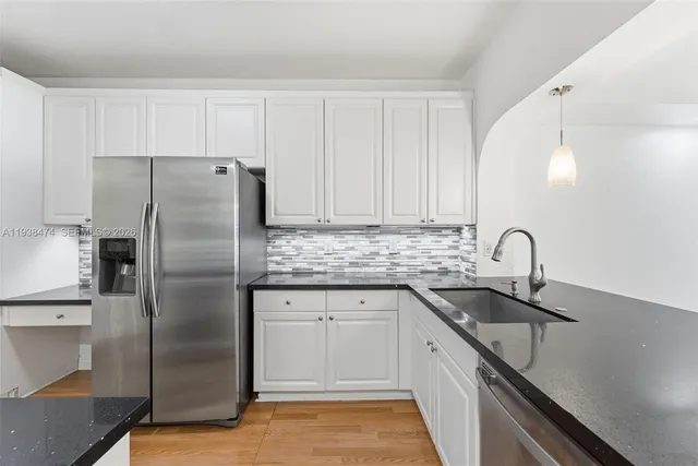 a kitchen with stainless steel appliances granite countertop a sink a refrigerator and a granite counter tops