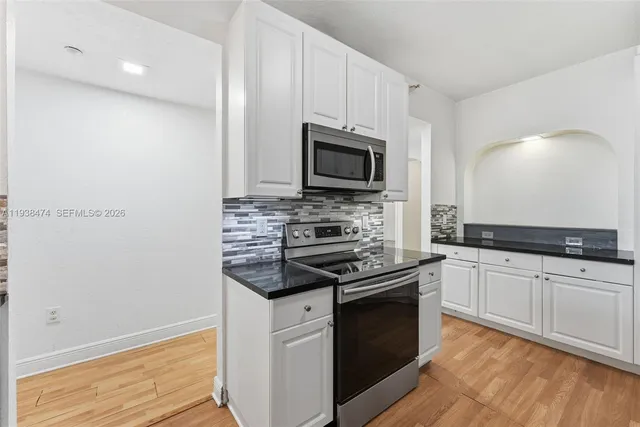 a kitchen with granite countertop white cabinets and stainless steel appliances