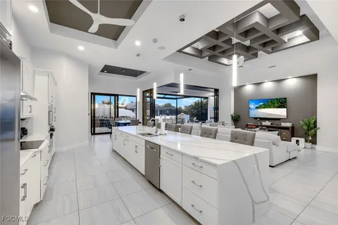 a large white kitchen with a large window a sink and stainless steel appliances