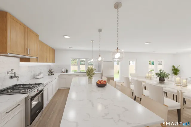 a large white kitchen with a large counter top space a sink stainless steel appliances and cabinets