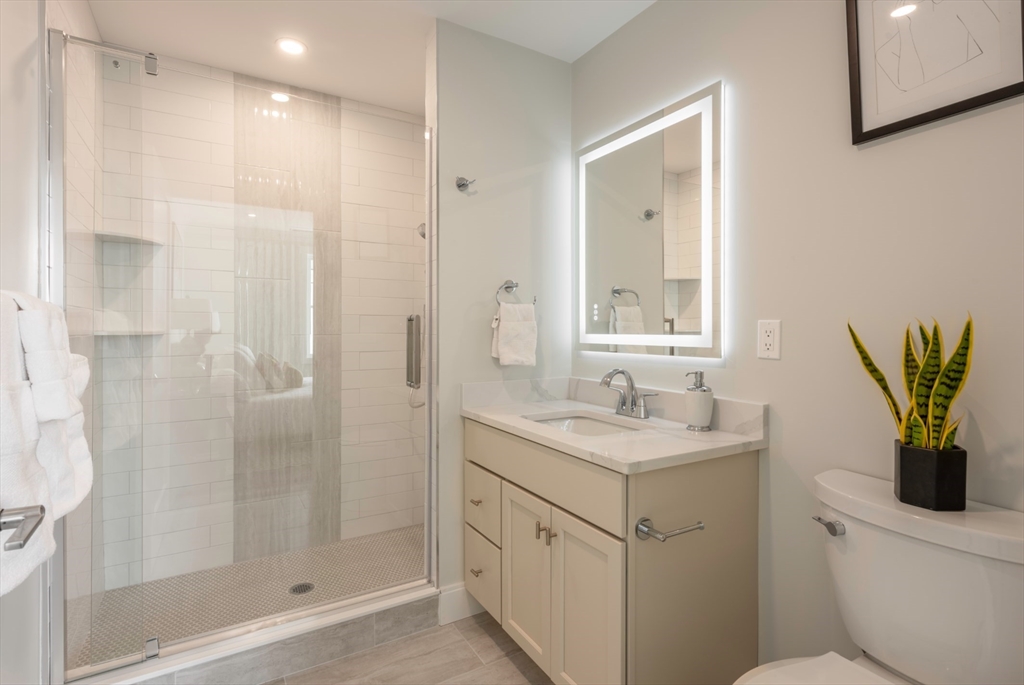 61 County Street, Unit 304 Dover, MA 02030 - Photo 6 of 8 a bathroom with a granite countertop sink a mirror a shower and a toilet