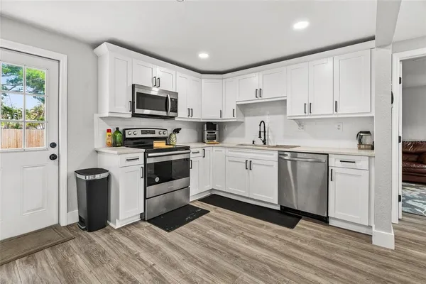 a kitchen with white cabinets stainless steel appliances and a window