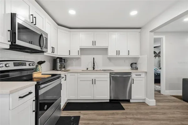 a kitchen with stainless steel appliances granite countertop white cabinets a sink a stove a microwave and wooden cabinets