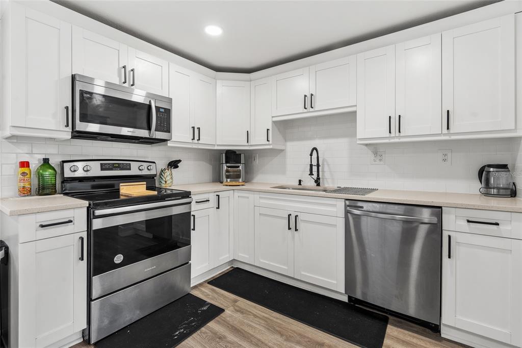 5135 Bradenton Road Sarasota, FL 34234 - Photo 14 of 30 a kitchen with stainless steel appliances granite countertop white cabinets a sink a stove a microwave and wooden cabinets
