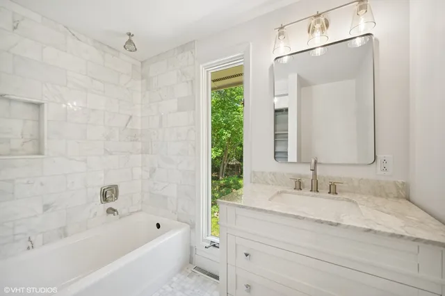a bathroom with a granite countertop sink a mirror a bathtub and a shower