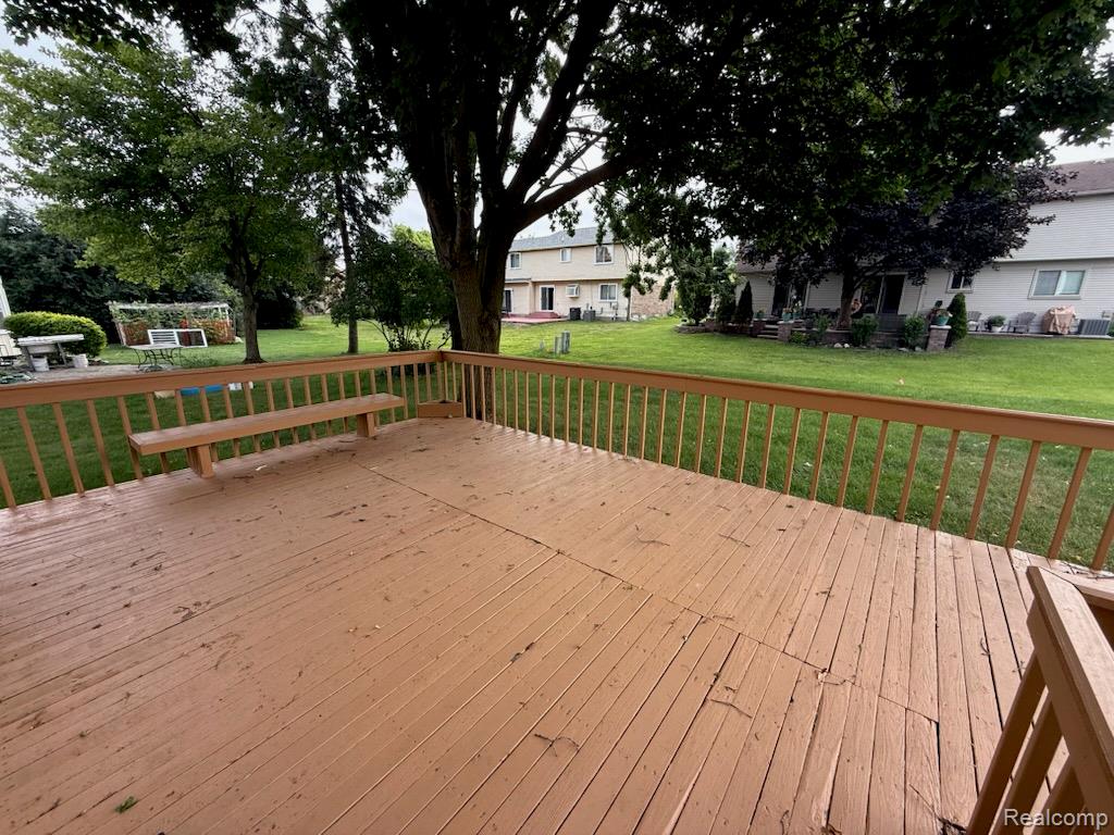 28144 Yorktown Road Farmington, MI 48331 - Photo 23 of 25 Wood-finish deck with integrated seating, overlooking a expansive green lawn with mature trees and perimeter fencing