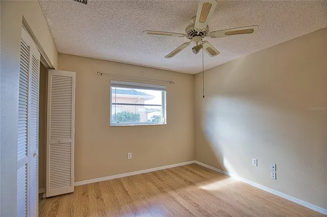 an empty room with wooden floor fan and windows