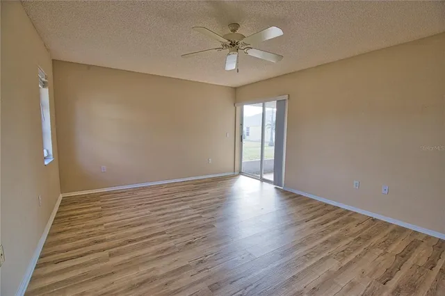 a view of an empty room with a window and wooden floor