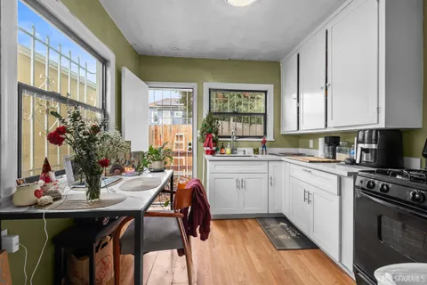 a kitchen with a dining table chairs stove and white cabinets