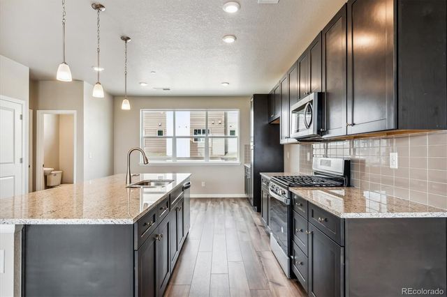 a kitchen with stainless steel appliances granite countertop a stove a sink and a refrigerator
