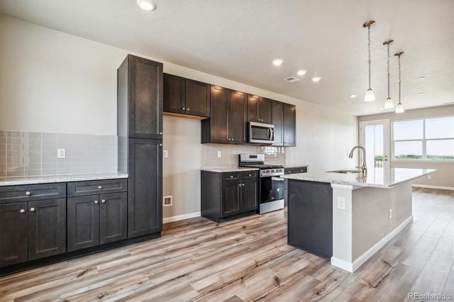 a kitchen with stainless steel appliances kitchen island granite countertop a large stove a sink dishwasher and a refrigerator with wooden floor