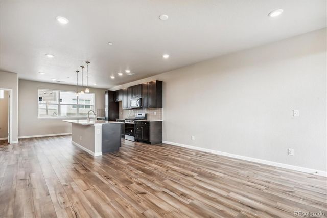 a large white kitchen with kitchen island a sink dishwasher a stove and a refrigerator with wooden floor