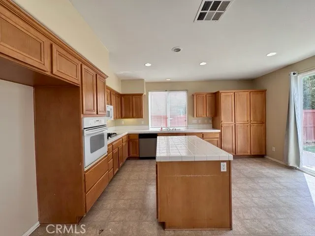 a large kitchen with stainless steel appliances kitchen island granite countertop a refrigerator a stove a sink and a cabinets