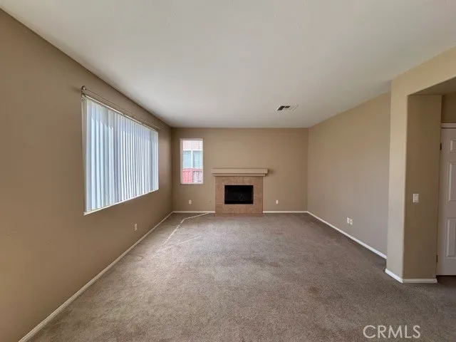 a view of an empty room with a window and fireplace