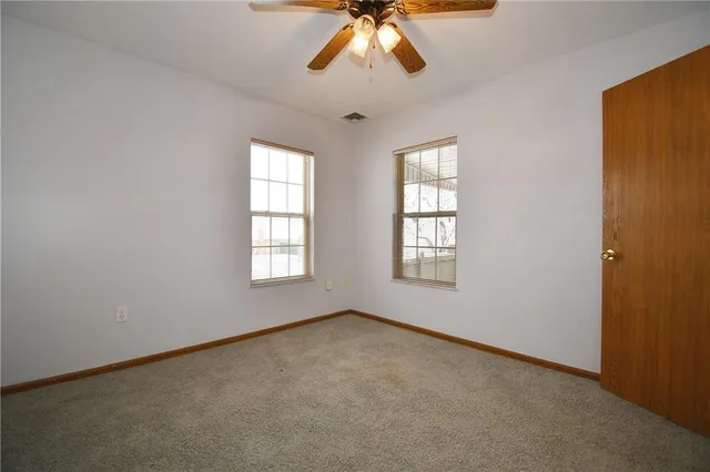a view of an empty room with window and chandelier fan