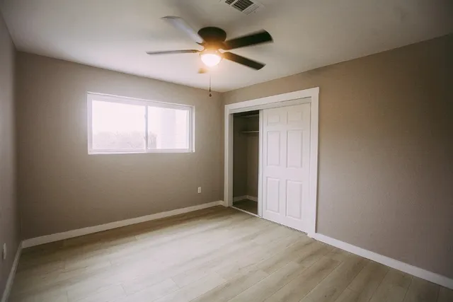 an empty room with ceiling fan and windows