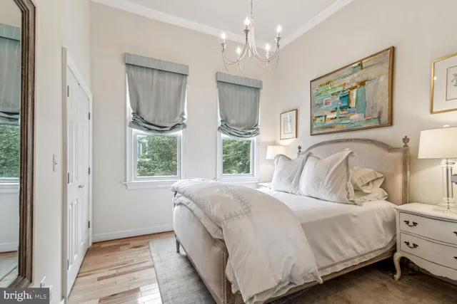 a bedroom with a bed chandelier and a window