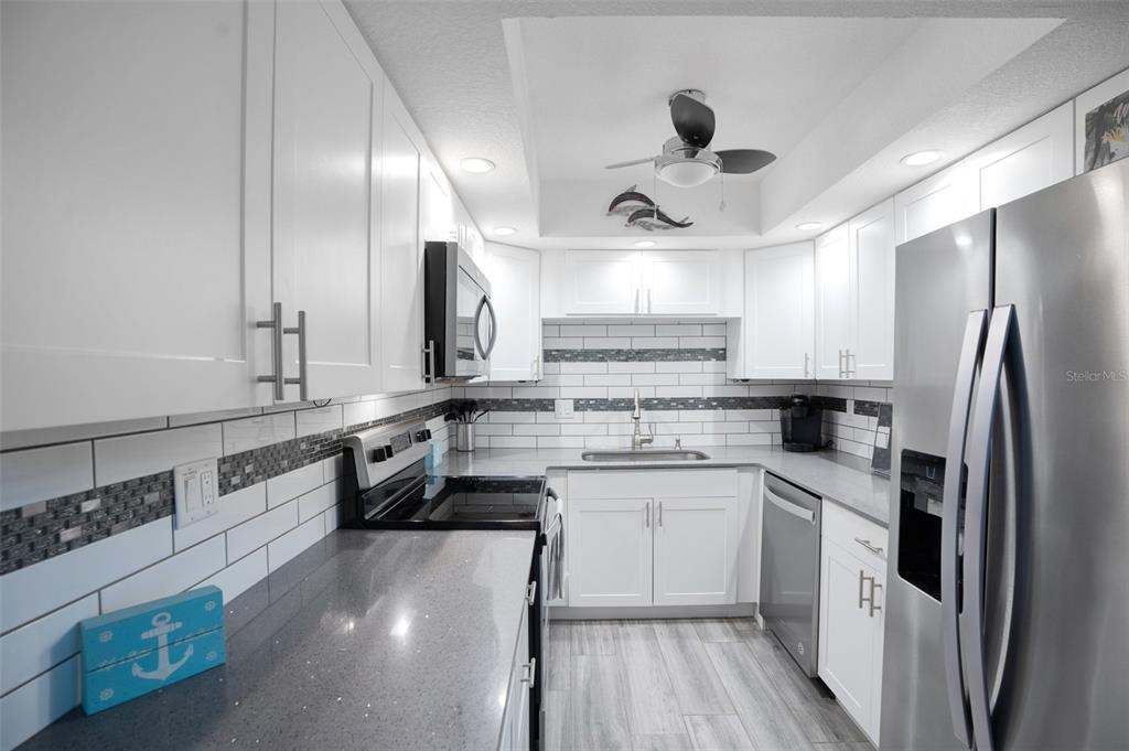 5855 Midnight Pass Road, Unit 327 Sarasota, FL 34242 - Photo 6 of 47 a kitchen with stainless steel appliances a sink stove and refrigerator