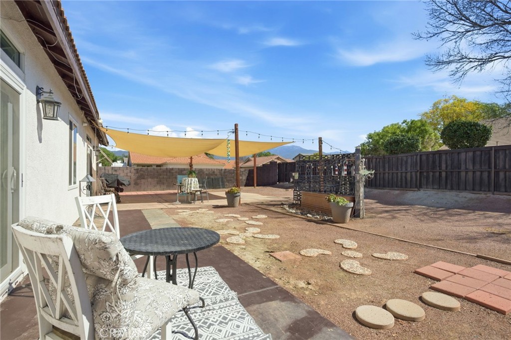 1853 Rue Chablis San Jacinto, CA 92583 - Photo 24 of 27 a view of a patio with a dining table and chairs with wooden fence