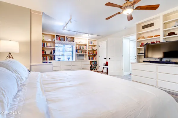 a bedroom with a bed and a flat tv screen on dresser