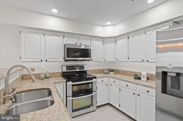 a kitchen with granite countertop white cabinets sink and stainless steel appliances