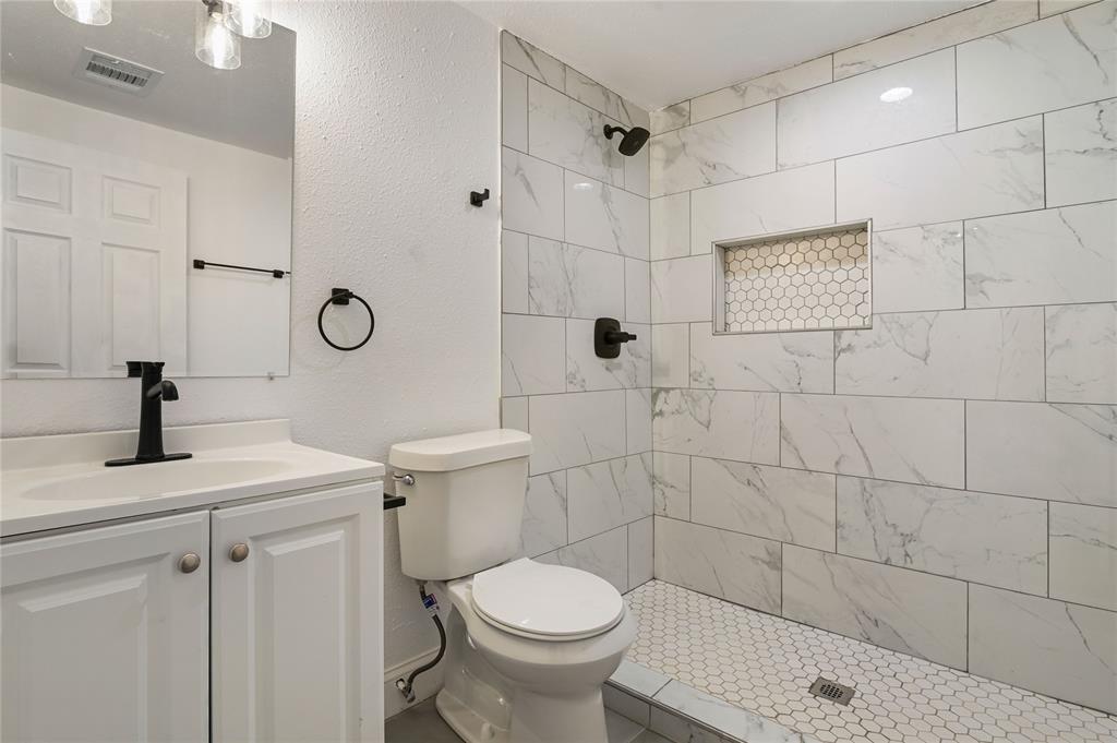 1106 West Chestnut Street Denison, TX 75020 - Photo 8 of 38 Bathroom with vanity, a tile shower, and toilet