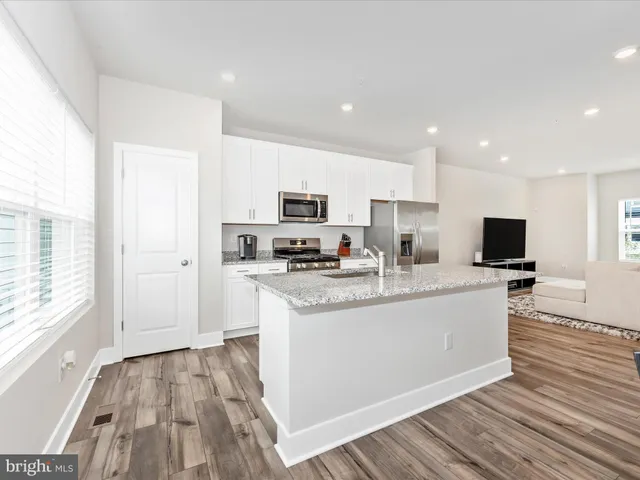 a kitchen with stainless steel appliances granite countertop a sink a stove a refrigerator and island with wooden floor