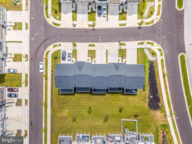 a sign that is sitting in front of a house with a large tree