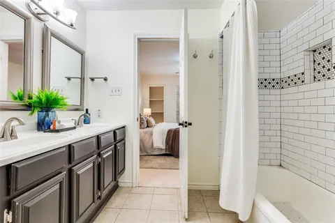 a bathroom with a double vanity sink a mirror a bathtub and shower