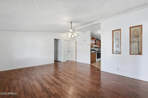 an empty room with wooden floor chandelier and windows