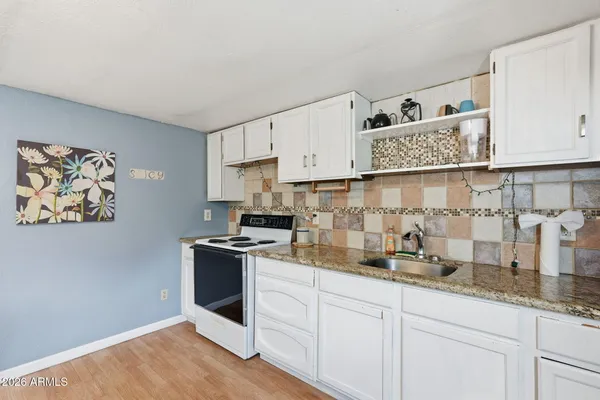 a kitchen with granite countertop white cabinets and white appliances