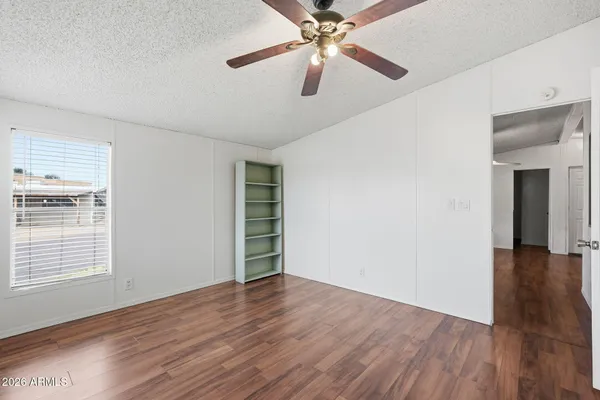 an empty room with wooden floor chandelier fan and windows
