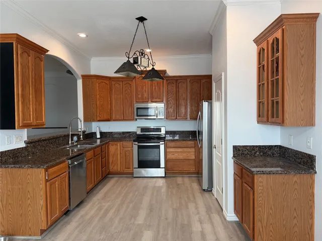 a kitchen with stainless steel appliances granite countertop a stove a sink dishwasher a refrigerator and a oven with wooden floor